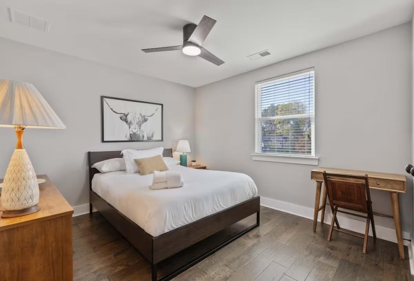 Spacious room featuring wood-finish flooring, a contemporary ceiling fan, and a large window with blinds