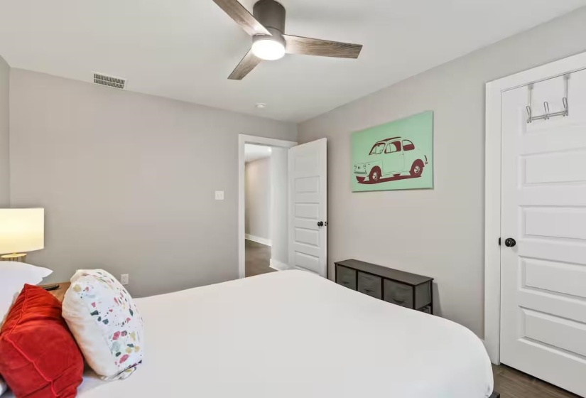 Bedroom featuring a modern ceiling fan with integrated lighting, a white paneled door with a black doorknob, and light gray wall paint