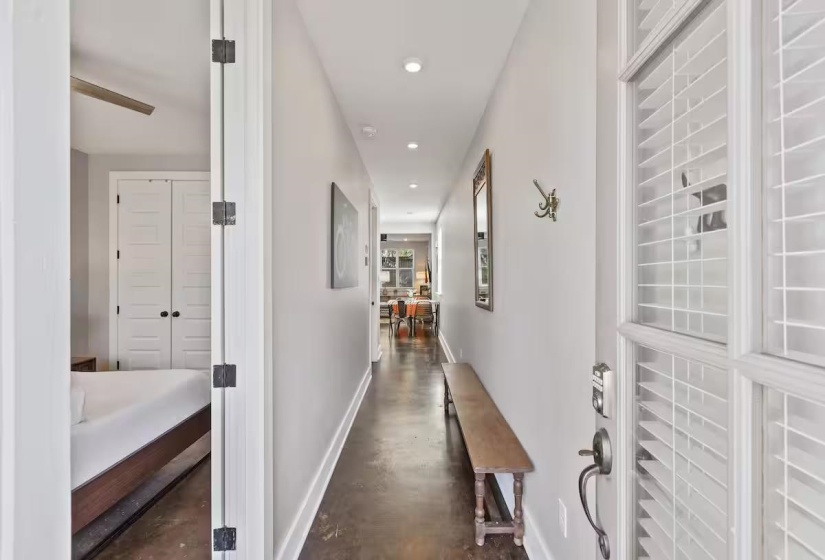 Entryway with a glass-paneled door featuring interior shutters, leading to a hallway with recessed lighting and a wood-finish floor