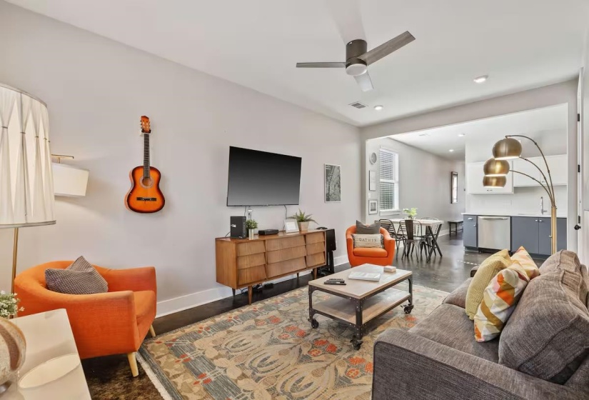 Open-concept living space featuring wood-finish flooring, a contemporary ceiling fan, recessed lighting, and a wide entryway to the kitchen area