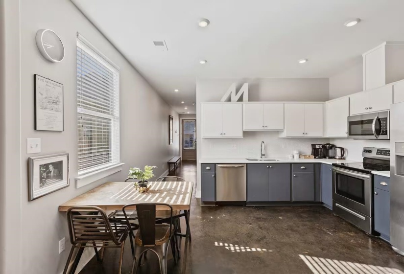 Open-concept kitchen featuring two-tone cabinetry, stainless steel appliances, and solid surface countertops