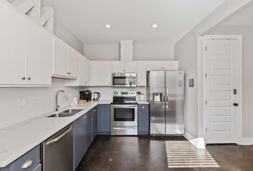 Contemporary kitchen featuring a dual-tone cabinetry design, white countertops, and full suite of stainless steel appliances