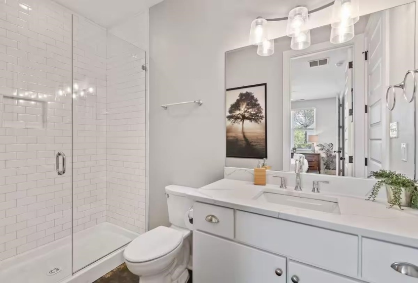 White subway tile shower enclosure with a clear glass door, complemented by a vanity featuring a white countertop, undermount sink, and chrome fixtures