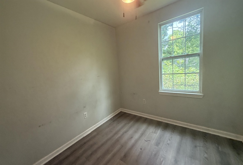 Room featuring wood-finish flooring, white baseboards, and a double-hung window with a white frame