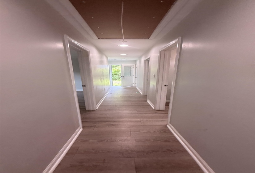 Hallway featuring wood-finish flooring, white baseboards, and light gray walls