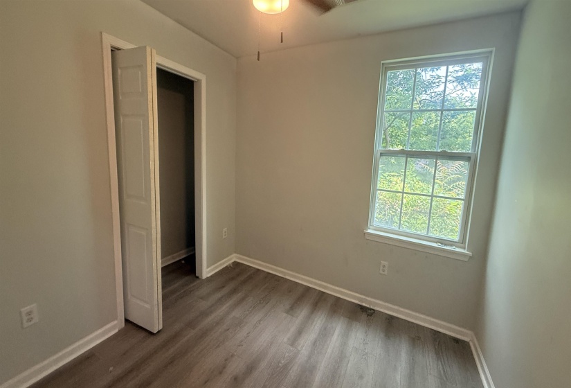 Neutral toned walls with white trim, wood-finish flooring, and a double-hung window