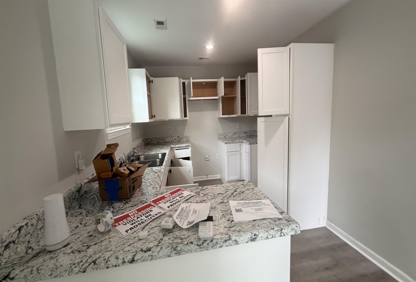 Kitchen featuring white cabinetry, light-toned countertops, and wood-finish flooring