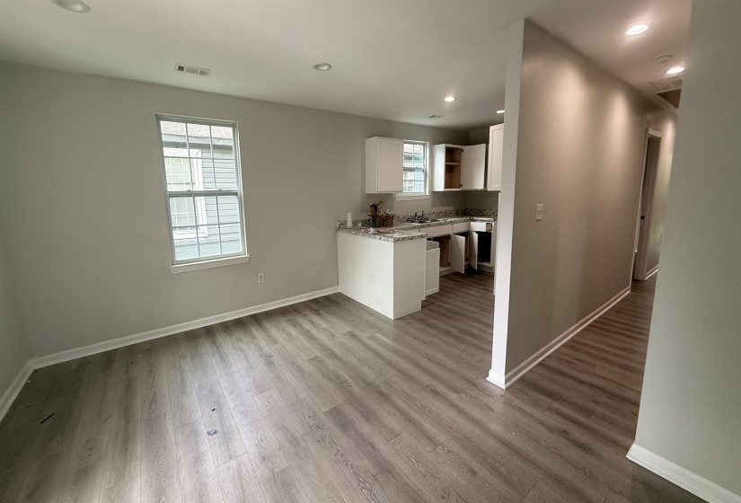 Open-concept living area featuring wood-finish flooring, recessed lighting, and a neutral color palette