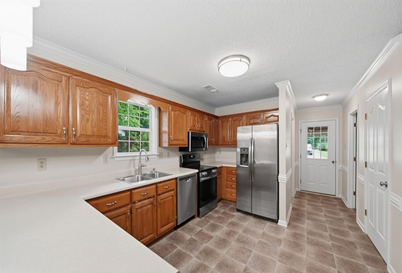 Open-concept kitchen and dining area featuring wood-finish cabinetry, stainless steel appliances, a breakfast bar, and double paneled glass doors