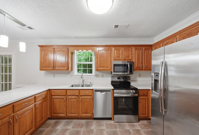 Kitchen featuring wood cabinetry, white countertops, stainless steel appliances, and a double basin sink