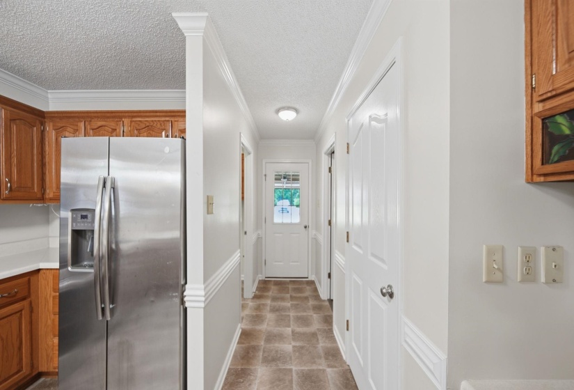 Hallway featuring neutral wall tones, crown molding, and a paneled door