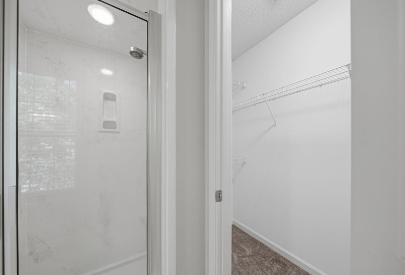 Walk-in shower with clear glass enclosure and walk in closet.