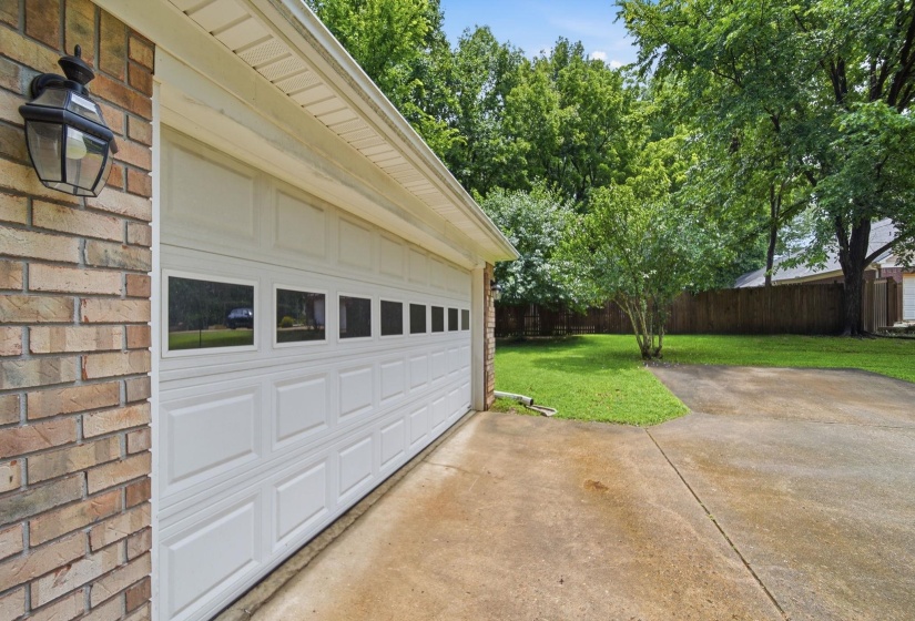 Brick exterior featuring a white paneled garage door with upper window inserts