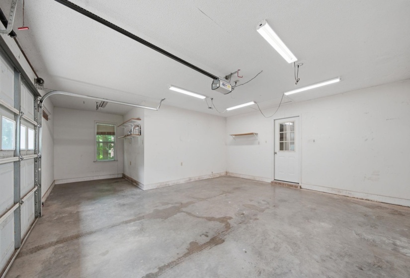 Spacious garage featuring a concrete floor, overhead fluorescent lighting, and a window for natural light