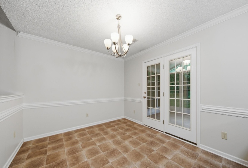 Dining area featuring vinyl flooring, a chandelier, and French doors.