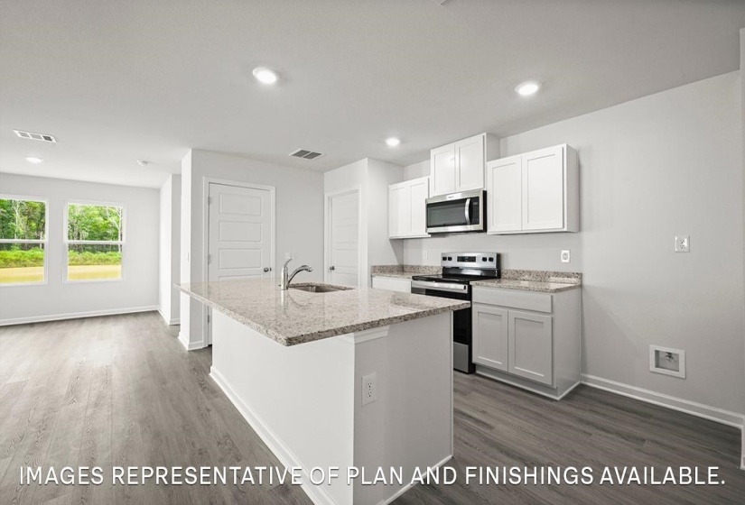 Kitchen island with granite-style countertop and integrated sink, stainless steel appliances, white cabinetry, wood-finish flooring, and recessed lighting