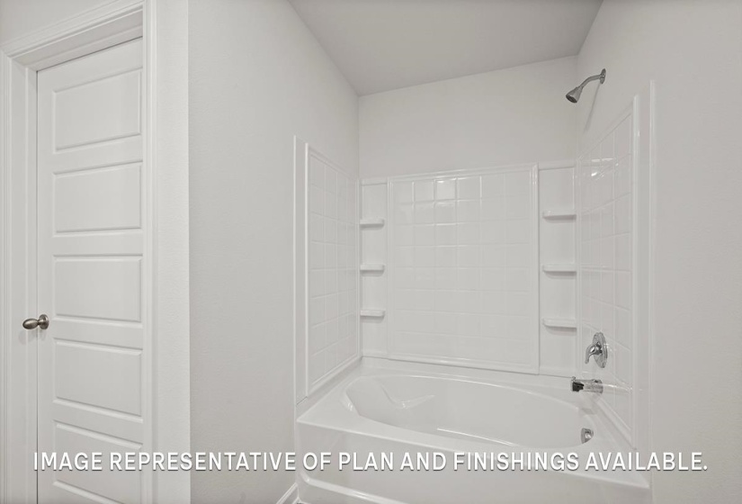 Bathroom featuring a white tub-shower combination with tiled surround, built-in shelving, and a chrome shower head and faucet