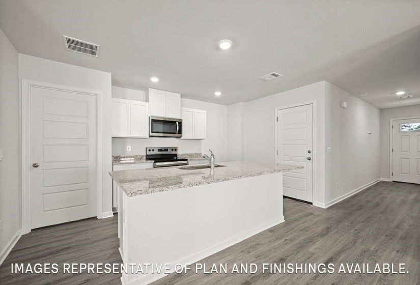 Contemporary kitchen featuring white cabinetry, a large center island with granite-style countertops, stainless steel appliances, and wood-finish flooring