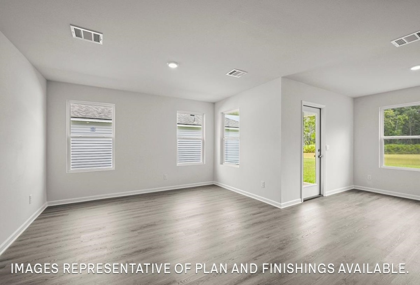 Spacious room featuring light wood-finish flooring, recessed lighting, multiple windows with blinds, and white baseboards