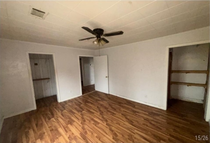 Spacious room featuring wood-finish flooring, white walls, and a ceiling fan