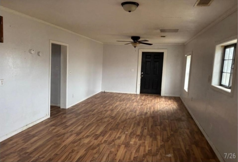 Spacious room featuring wood-finish flooring, white walls, and white baseboards