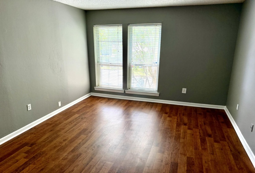 Interior space featuring wood-finish flooring, two large windows with blinds, and white baseboards
