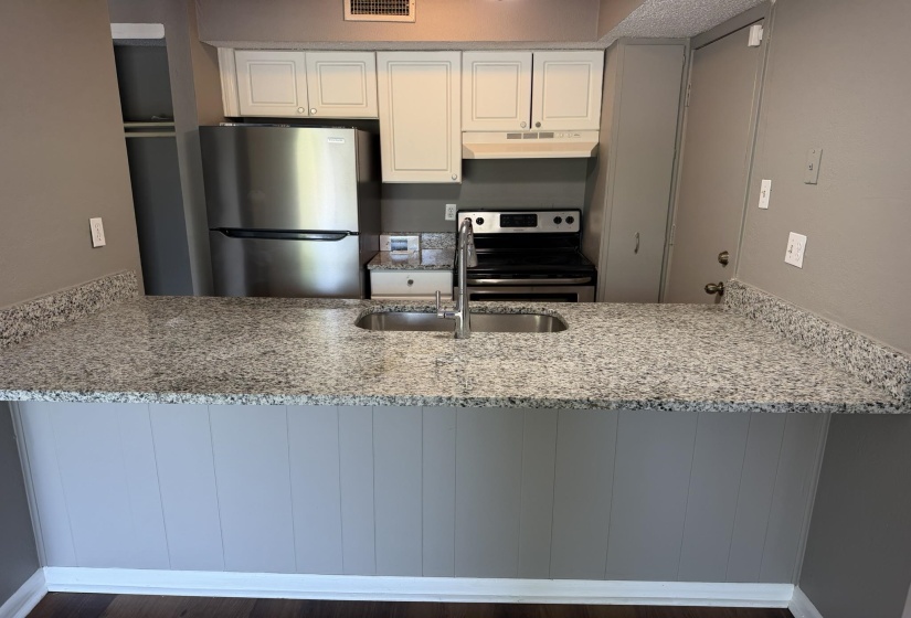 Kitchen featuring a breakfast bar with stone-finish countertops and an undermount stainless steel sink