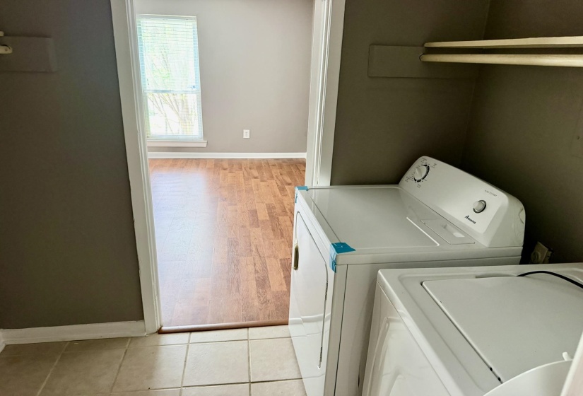Dedicated laundry area featuring a white top-load washer and dryer set, tiled flooring, and overhead shelving