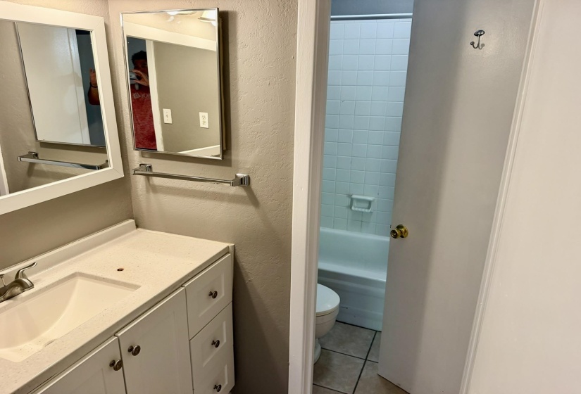 Bathroom vanity featuring a white framed mirror, chrome towel bar, and a single-basin sink set into a light-colored countertop