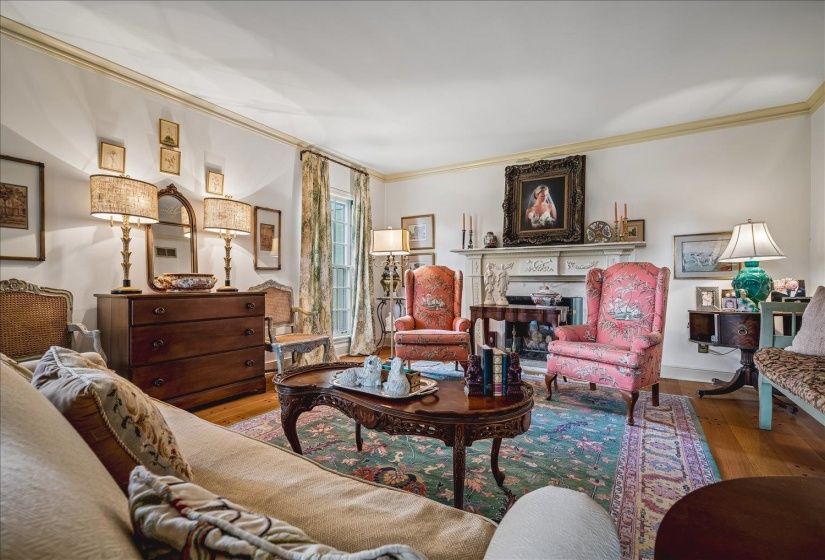Living area featuring hardwood flooring, a decorative fireplace with a mantel, and crown molding