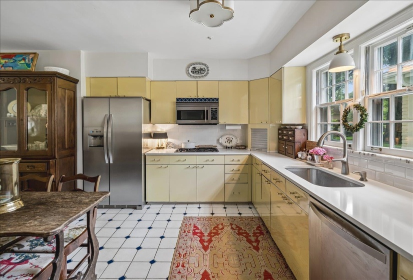 Kitchen featuring light yellow cabinetry, white countertops, tile backsplash, and stainless steel appliances