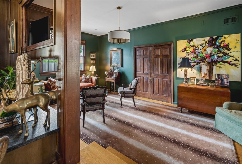 Interior space featuring deep green walls, hardwood flooring, a ceiling-mounted light fixture, and paneled double doors