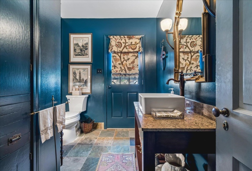 Bathroom featuring a wood vanity with a vessel sink, a complementary countertop, and multi-toned stone tile flooring