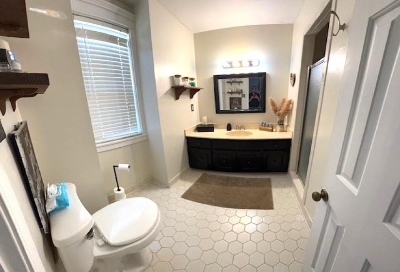Bathroom featuring hexagonal tile flooring, a dark wood-finish vanity with a light countertop, and a shower enclosure