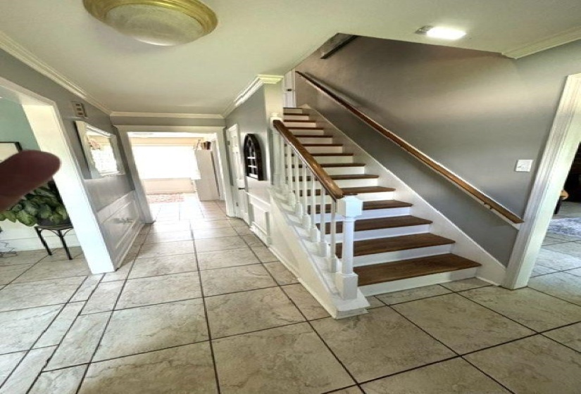 Foyer featuring a grand staircase with wood-finish treads and white risers, a wood handrail, and white balusters