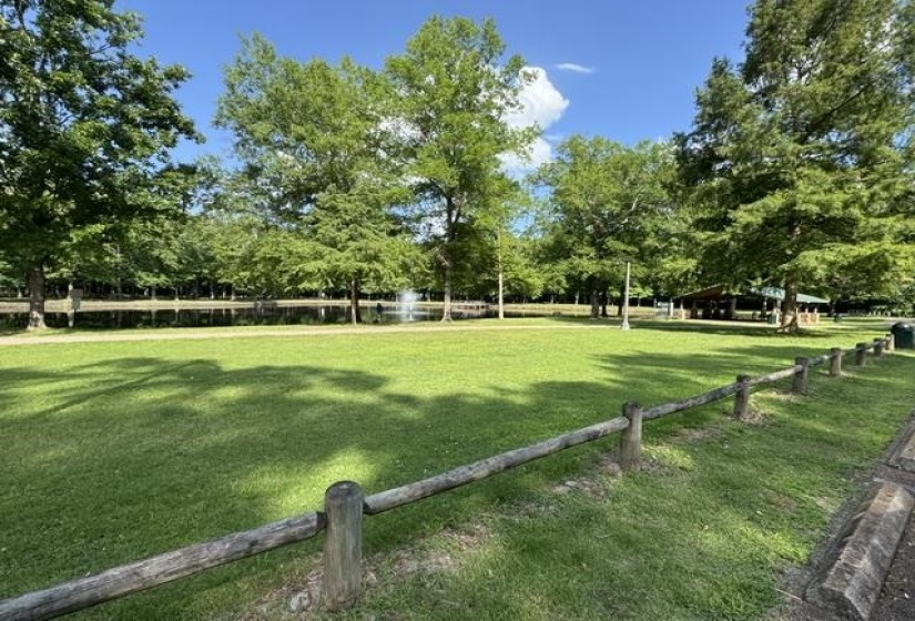 Expansive green space featuring a wooden split-rail fence and mature trees