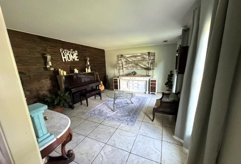 Spacious interior featuring a prominent wood plank accent wall, light-toned tile flooring, and neutral wall paint