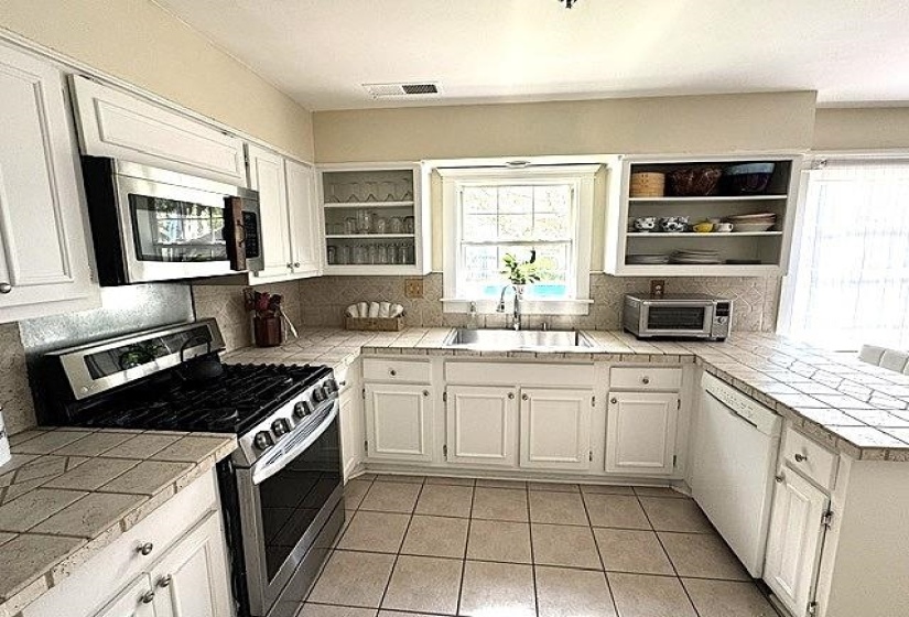 U-shaped kitchen featuring white cabinetry, tile countertops, and a tile backsplash
