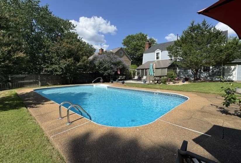In-ground swimming pool with integrated entry steps and a surrounding aggregate concrete deck