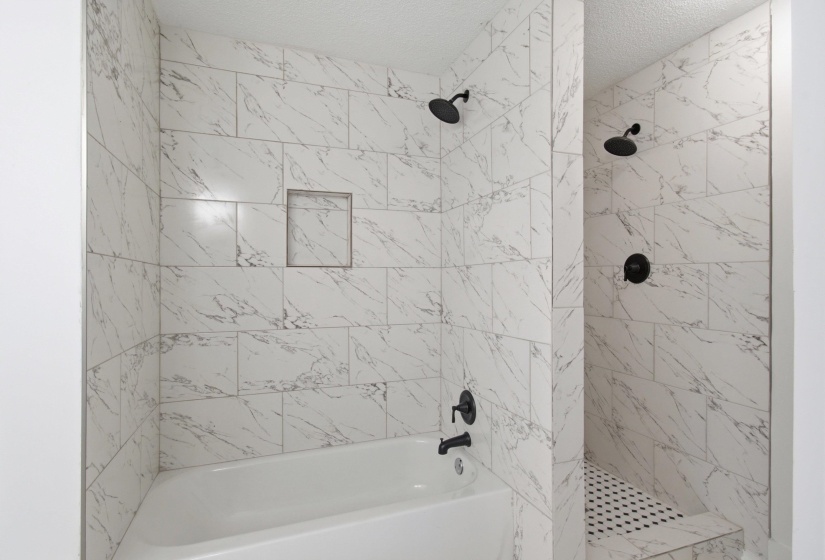 White-tiled shower and tub combination featuring black fixtures