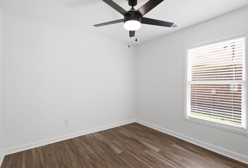 Room featuring wood-finish flooring, white walls, and a window with blinds