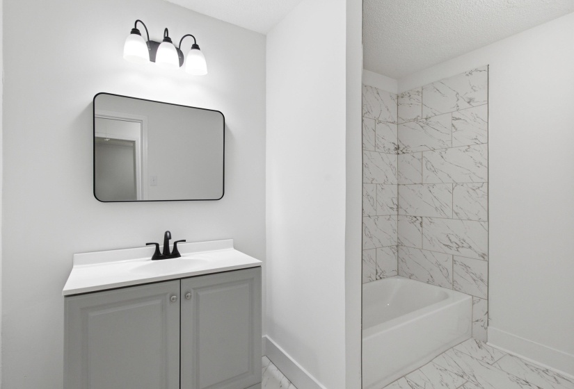 Bathroom featuring a light gray vanity with a white countertop and matte black fixtures