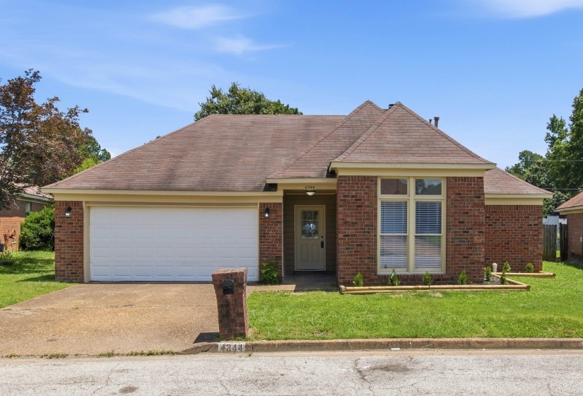 Brick exterior featuring an attached garage, front entryway, and multiple windows
