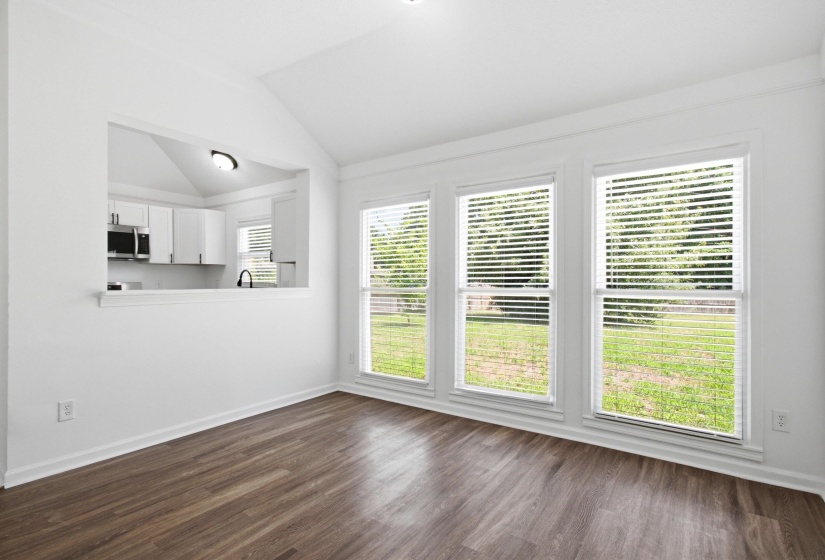 Interior space featuring vaulted ceilings, wood-finish flooring, and a pass-through window to the kitchen