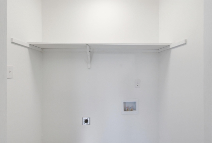 Laundry area featuring a built-in white shelf, electrical outlet, and plumbing connections