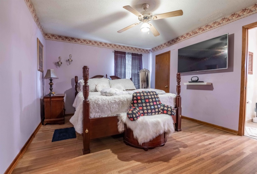 Spacious room featuring wood-finish flooring, a ceiling fan with integrated lighting, and light purple walls