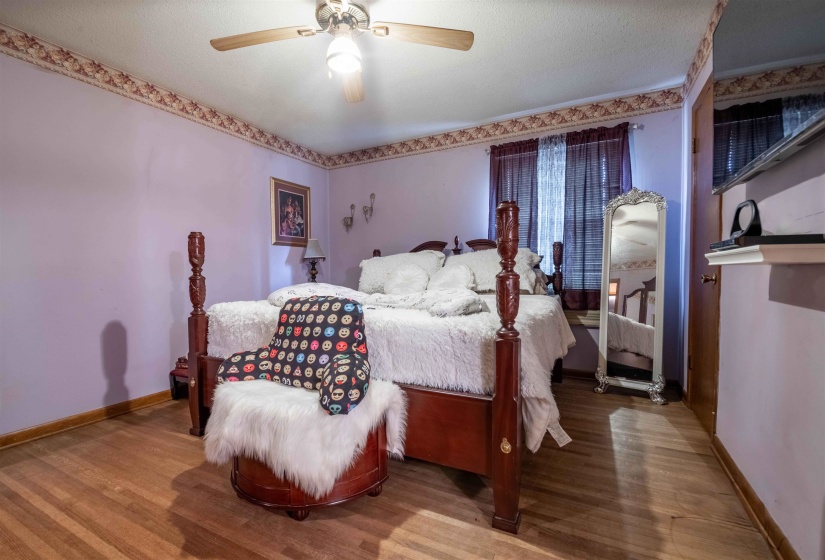 Spacious bedroom featuring wood-finish flooring and a ceiling fan with integrated lighting
