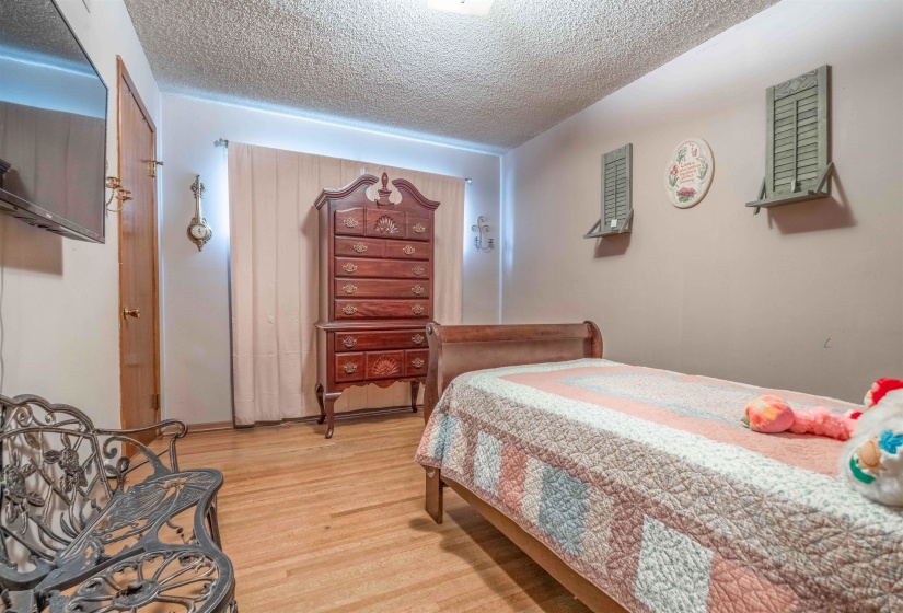 Light wood-finish flooring complements the neutral wall color in this room featuring a textured ceiling