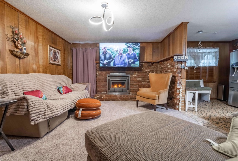 Wood-paneled living area featuring a brick fireplace and hearth