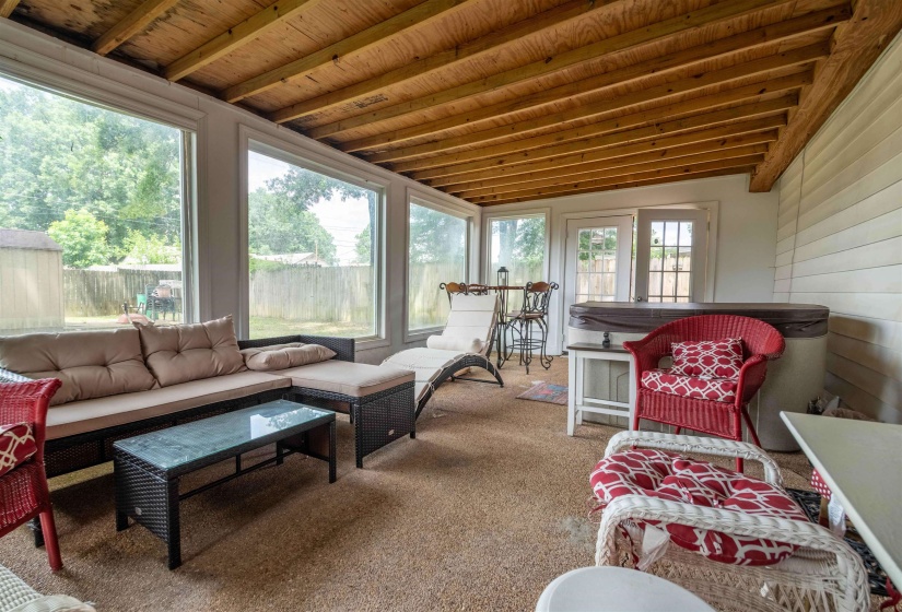 Enclosed patio featuring a wood-finish exposed beam ceiling, full-height windows, wall-to-wall carpeting, and a built-in spa